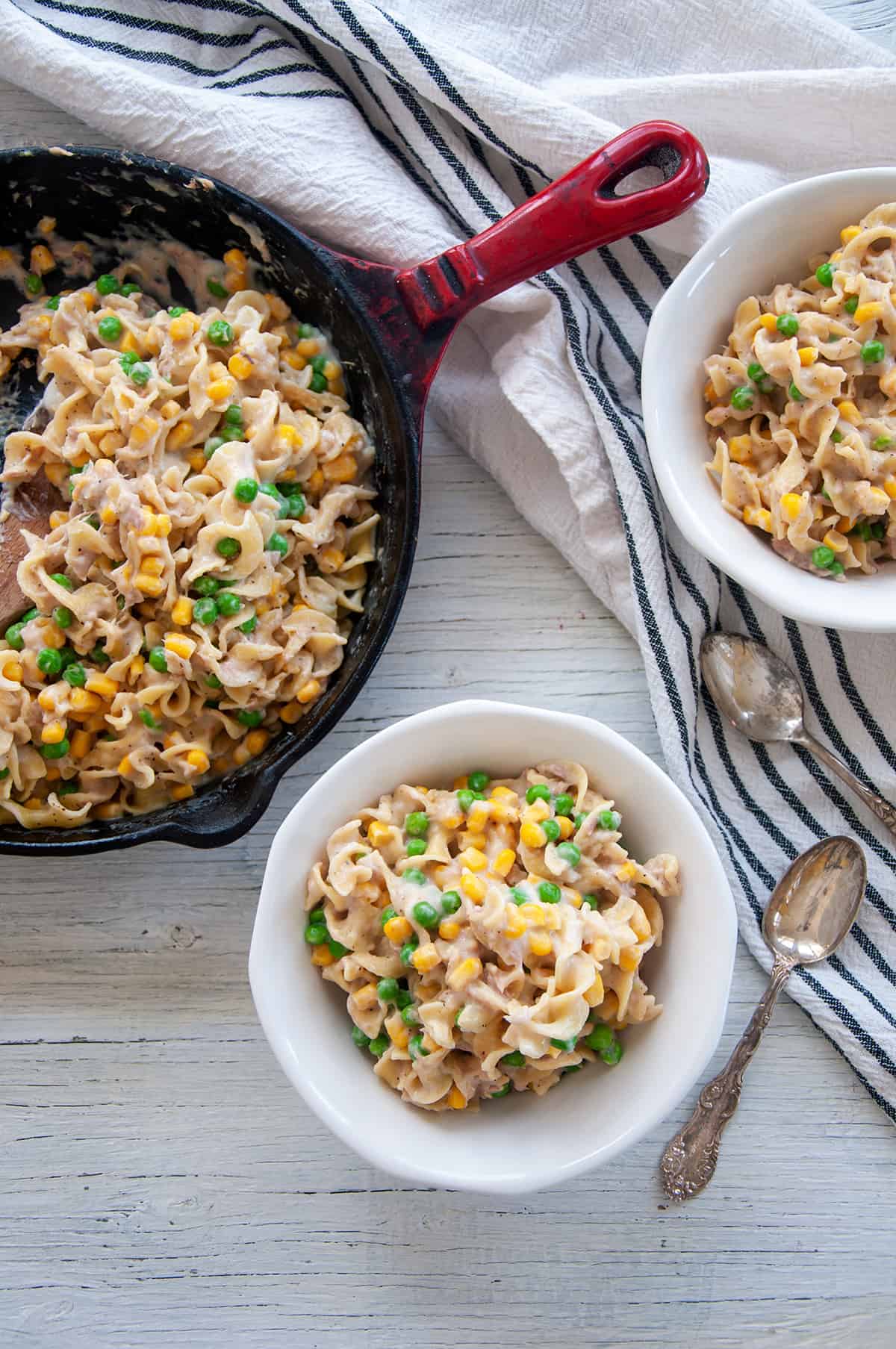 Homemade Skillet Tuna Helper Recipe in two white bowls with the remaining in a red cast iron skillet.