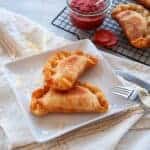 Two fried Italian Panzerotti on a white plate with a fork to the side.