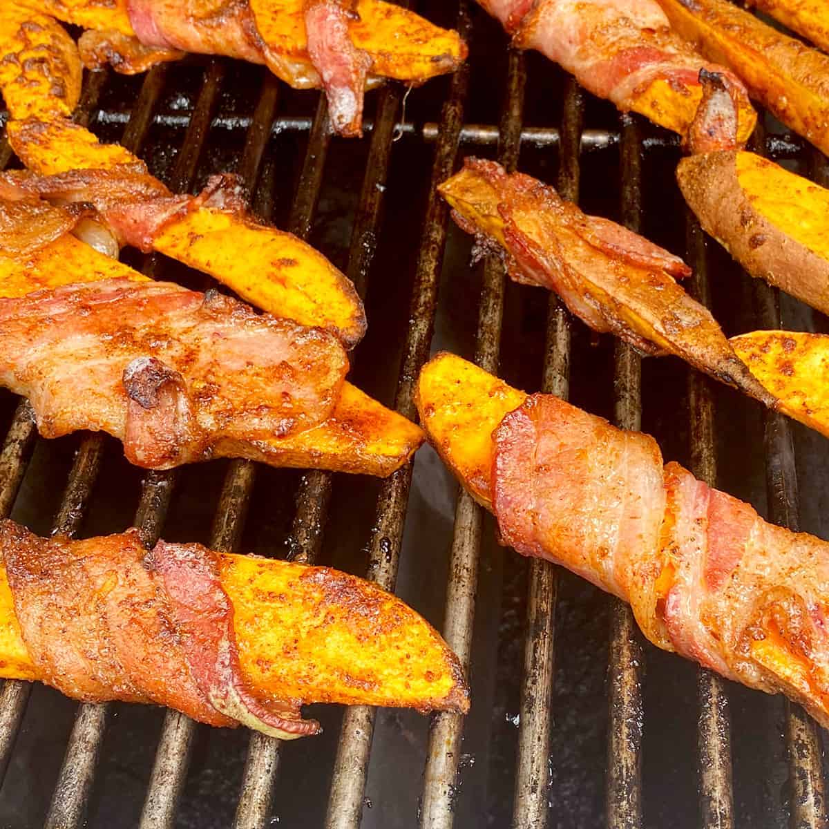 Bacon-wrapped sweet potato fries on the grill cooking.