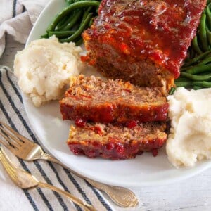 Spicy Italian Meatloaf on a big platter with mashed potatoes and green beans.