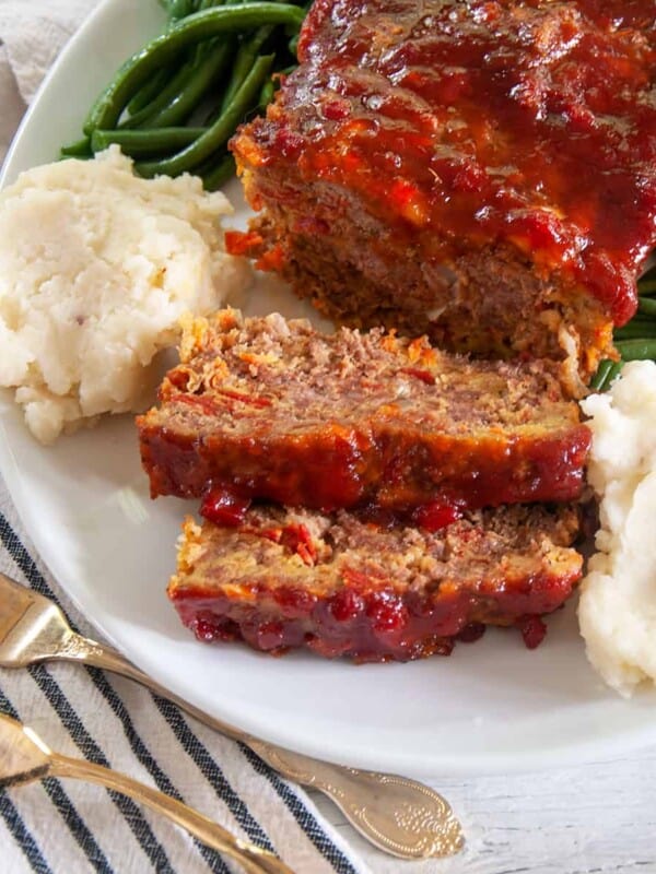 Spicy Italian Meatloaf on a big platter with mashed potatoes and green beans.