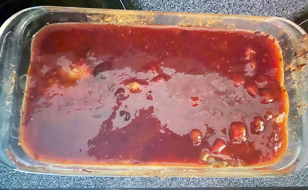 Loaf of unbaked meatloaf with glazed topping.
