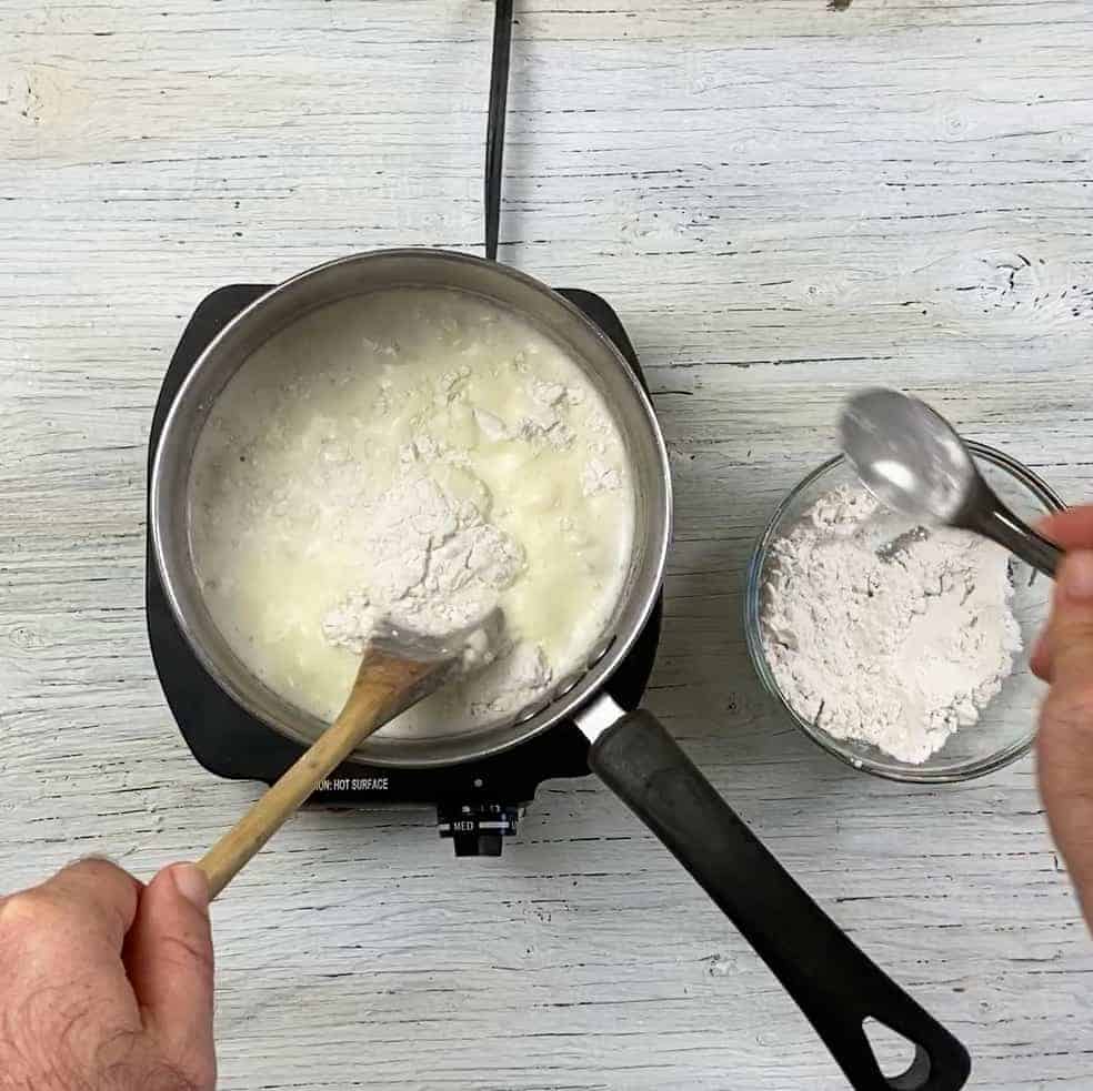 Mixing in flour into a pot of the sour cream that will turn into the Rømmegrøt.