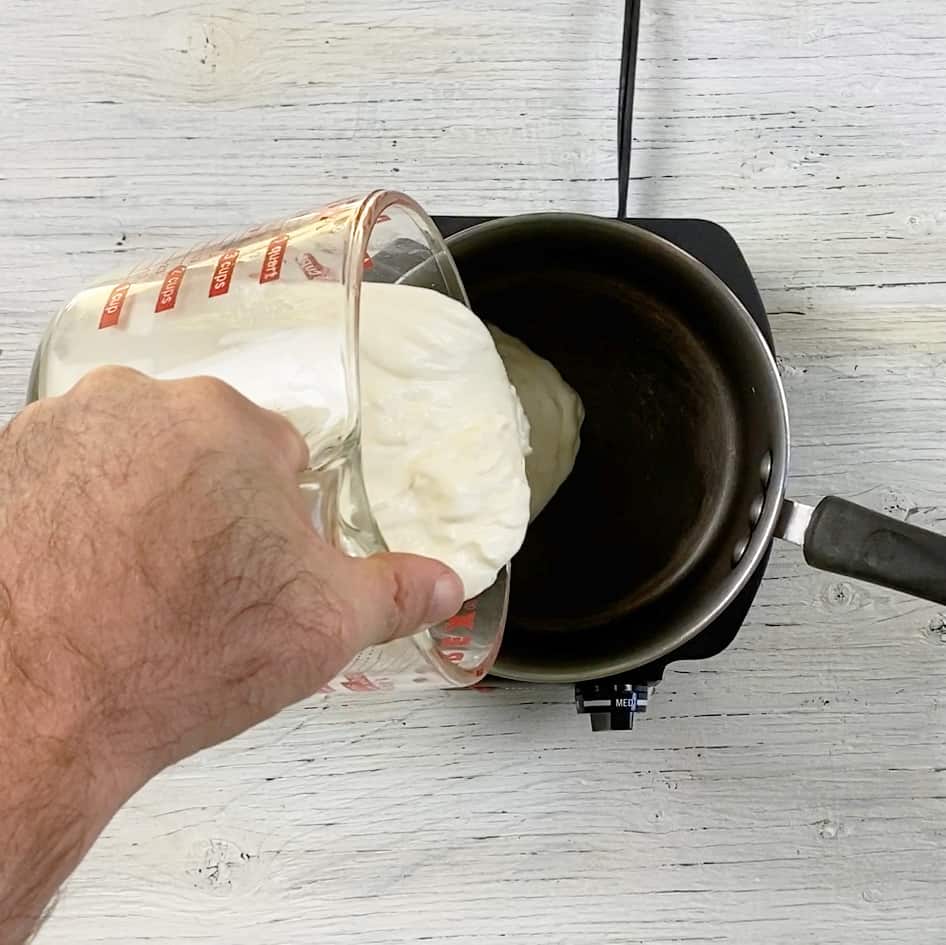 Pouring sour cream into a sauce pan.