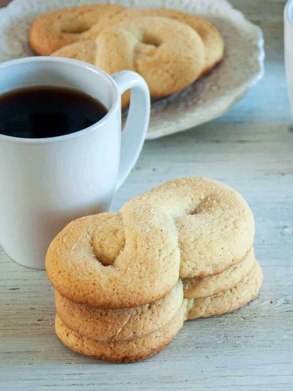 Three kringler cookies stacked on top of each other with a white mug of coffee showing to the side.