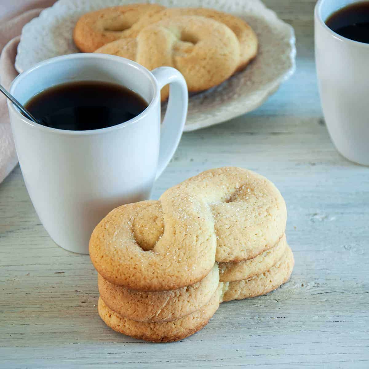 Three kringler cookies stacked on top of each other with a white mug of coffee showing to the side.