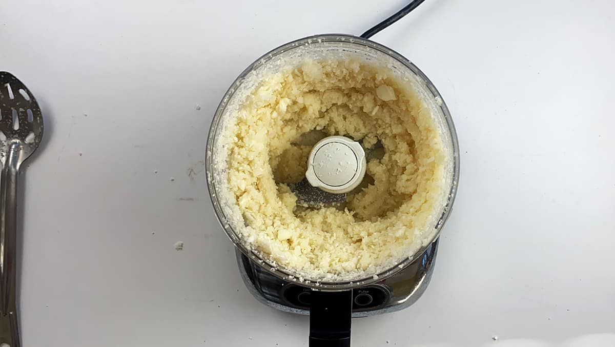 Cauliflower in a food processor that has been blended to a fine consistency.