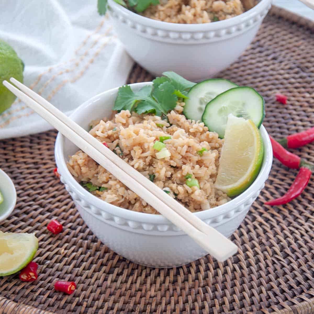 A bowl of Crab Fried Rice in a white bowl that is garnished with cilantro, cucumbers, lime.