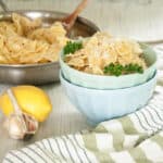 Creamy Lemon Pasta over Farfalle in a light blue bowl and the entire dish right behind it.