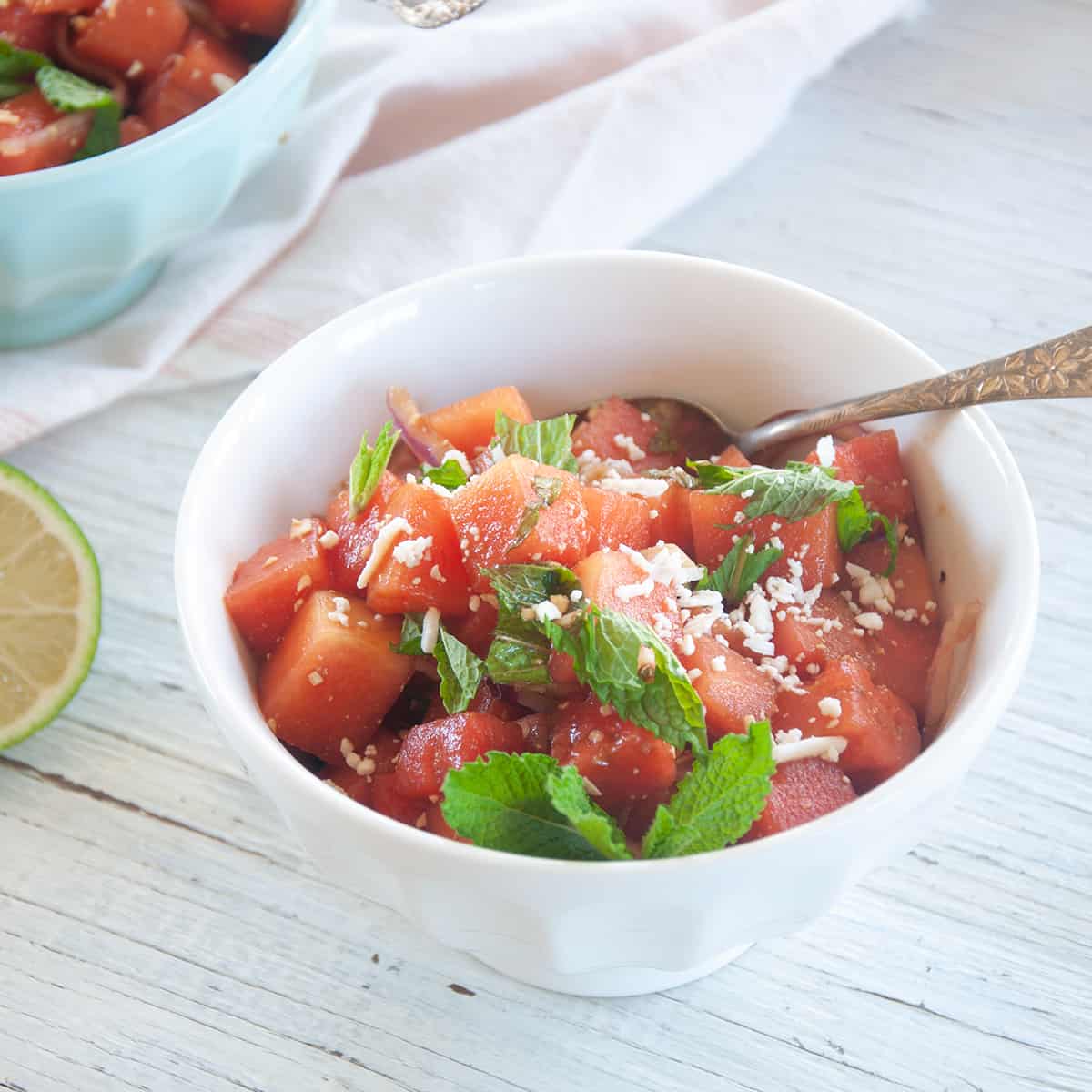 Bowl of Watermelon Feta Salad with balsamic vinegar on top and garnished with mint.