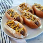 Five brats in buns and topped with onions and mustard.