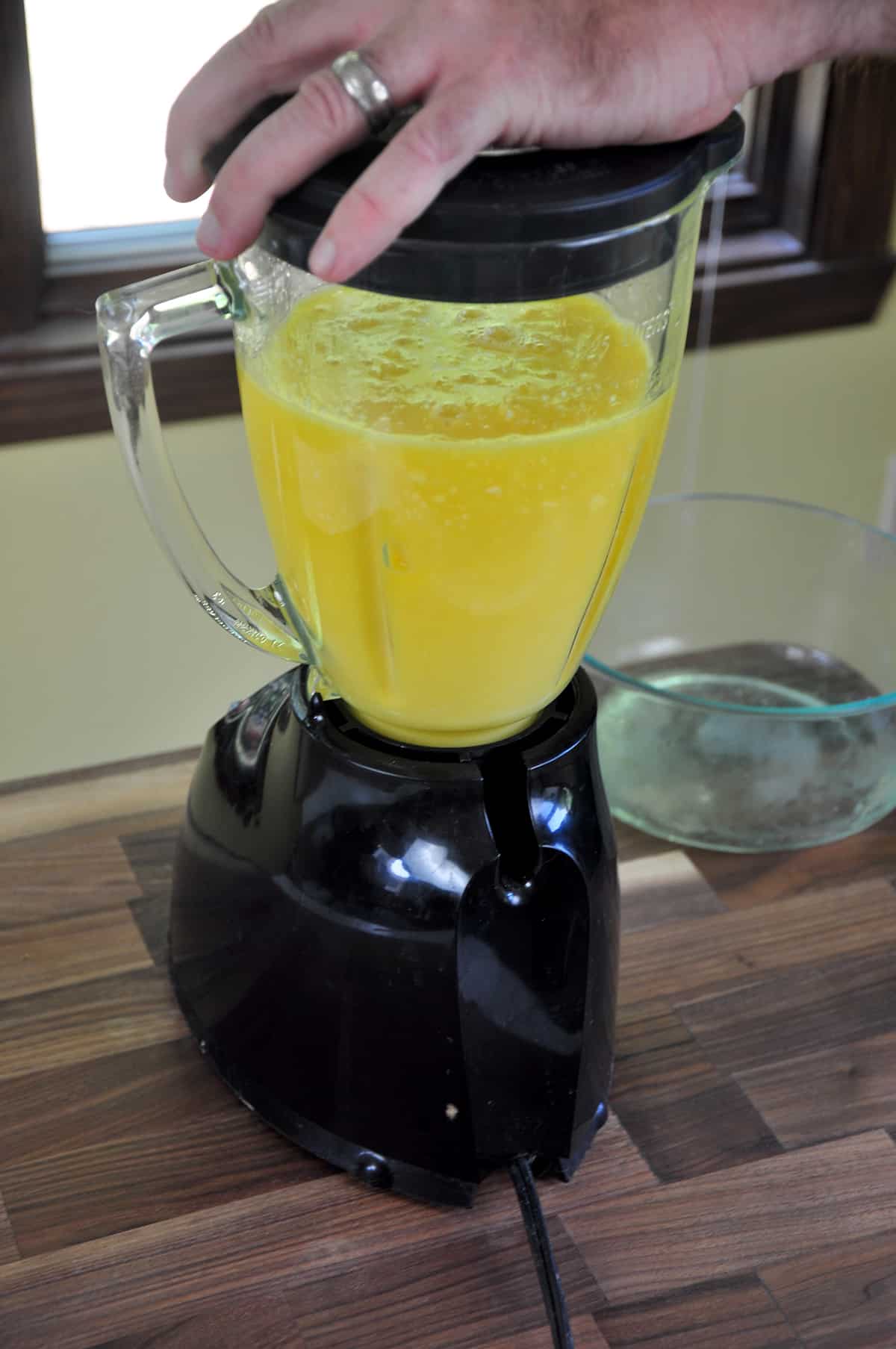 Hand over blender while mixing frozen mango mixture.