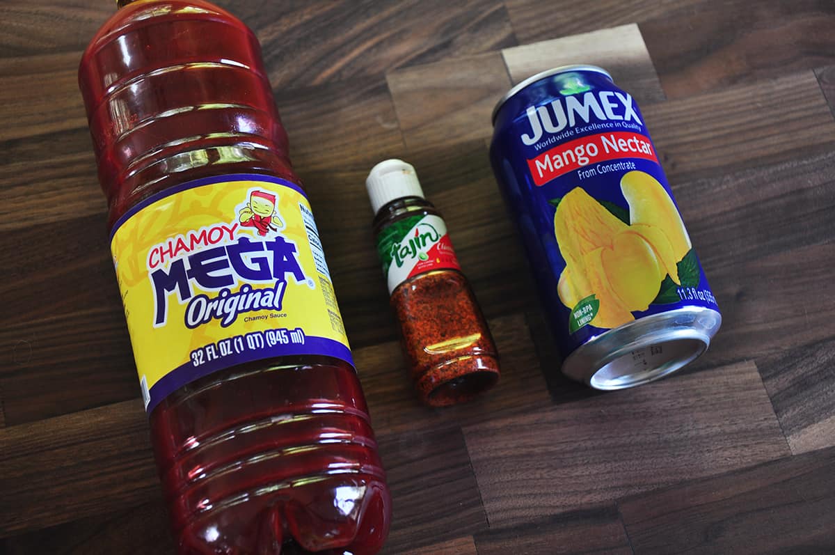 Chamoy, Tajin, and Mango Nectar laid out on a wood cutting board.