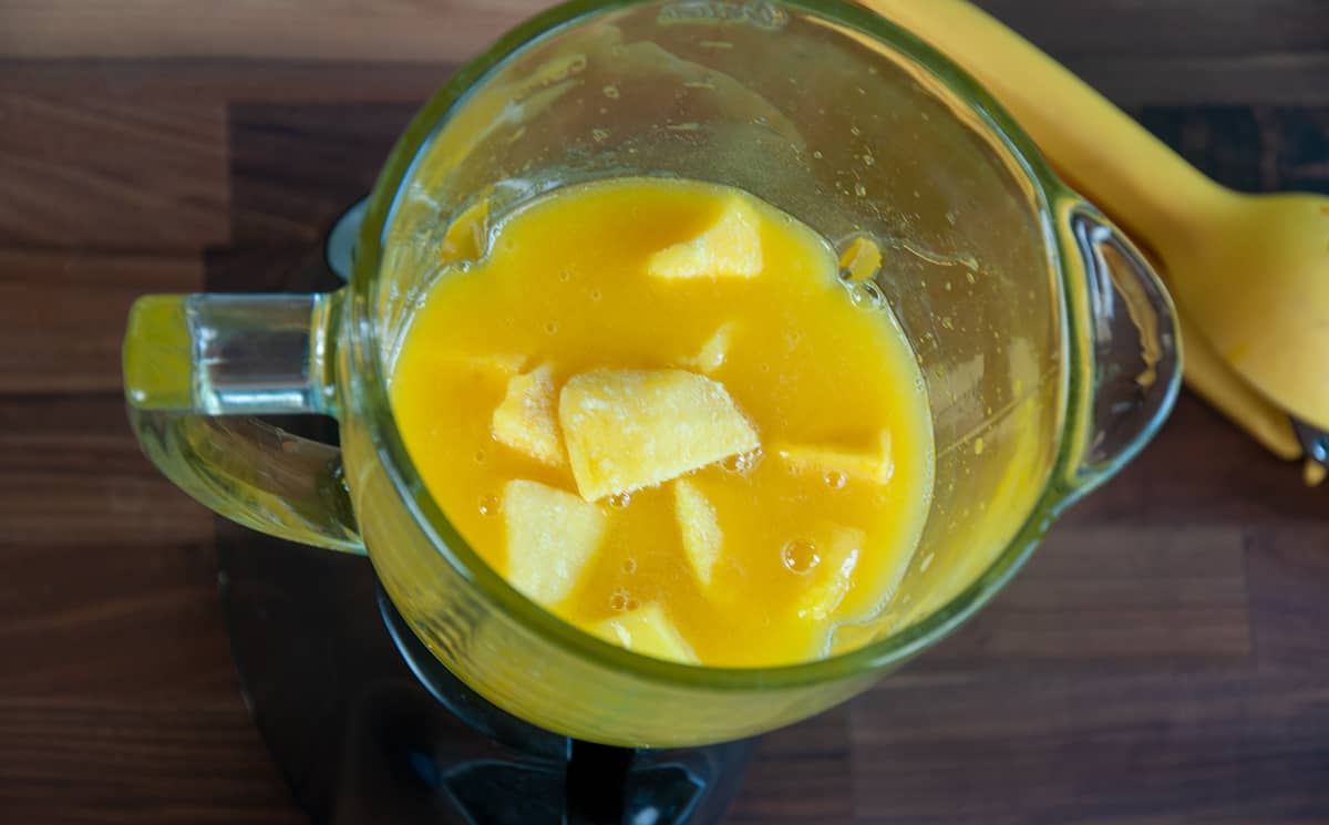 Blender filled with frozen mango and juice.