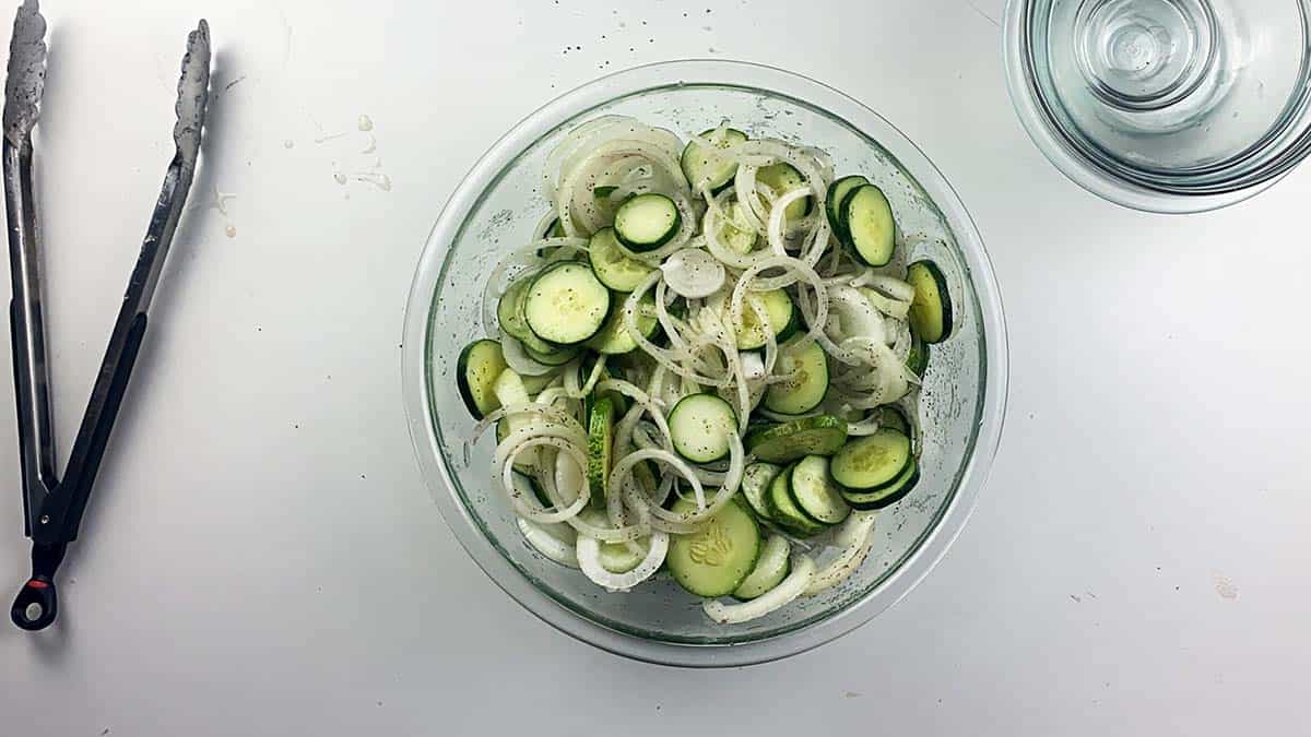 Onions, cucumbers, sugar, vinegar, and celery seed in bowl.