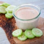 Chipotle Ranch Dressing and Dip on a cutting board with a cucumbers off to the side.