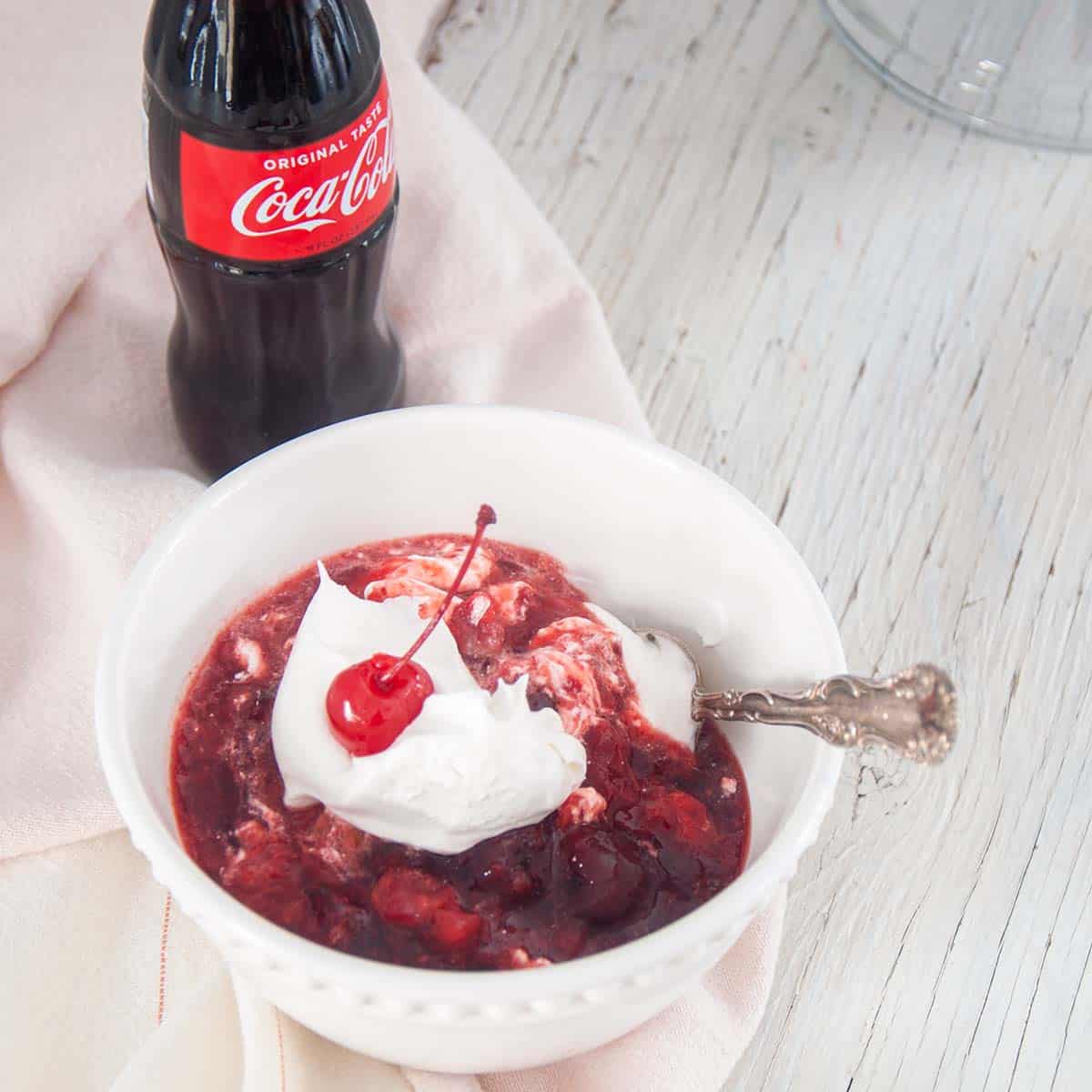 Single Serving of Coca-Cola Salad in a white bowl and topped with Cool Whip.
