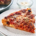 Chicago Deep Dish Pizza on a white table and a dish of cheese to the side.