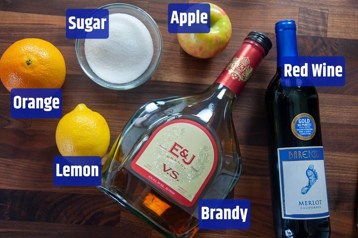 Sugar, apple, red wine, brandy, lemon, and sugar on a cutting board.