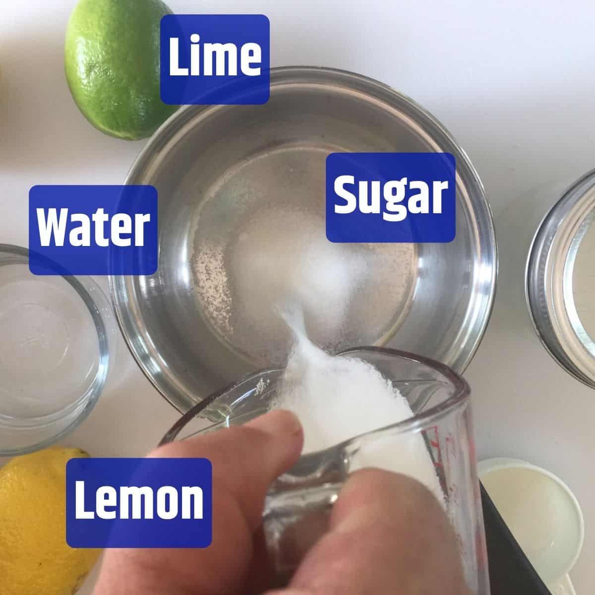 Pouring sugar into water with lemon and lime on a table.
