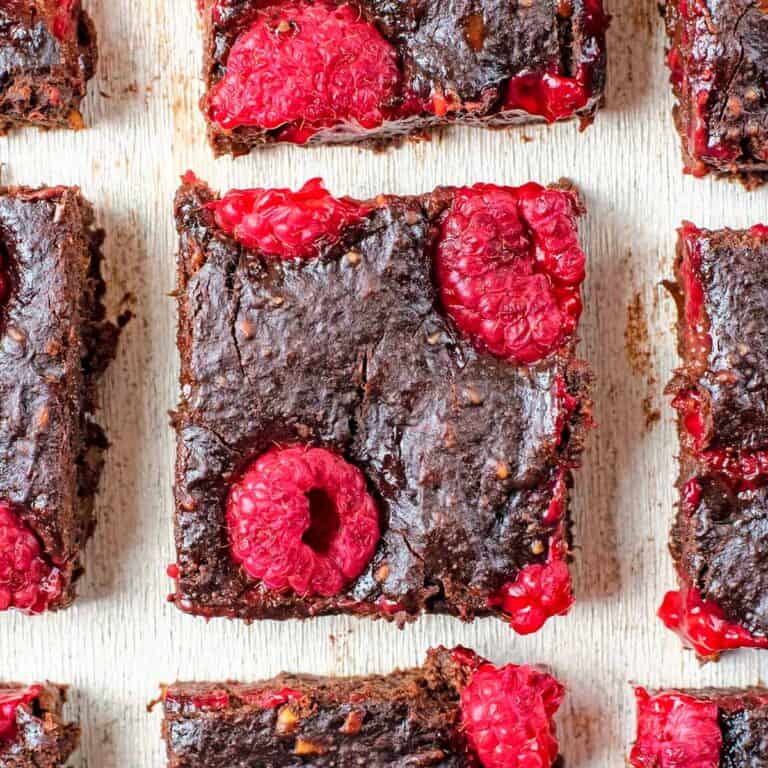 Several Healthy Chocolate Raspberry Brownies on a white table.