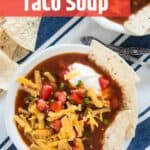 Bowl of taco soup with cheese, tomatoes, and sour cream on top.