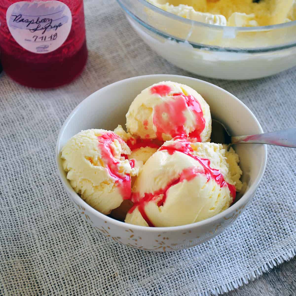Bowl of vanilla ice cream with raspberry topping.
