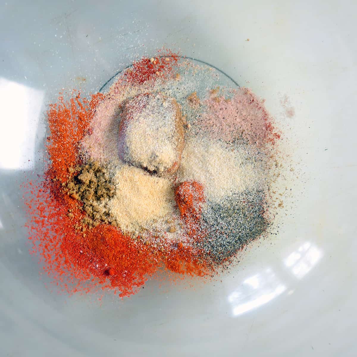 A variety of spices in a large glass bowl.