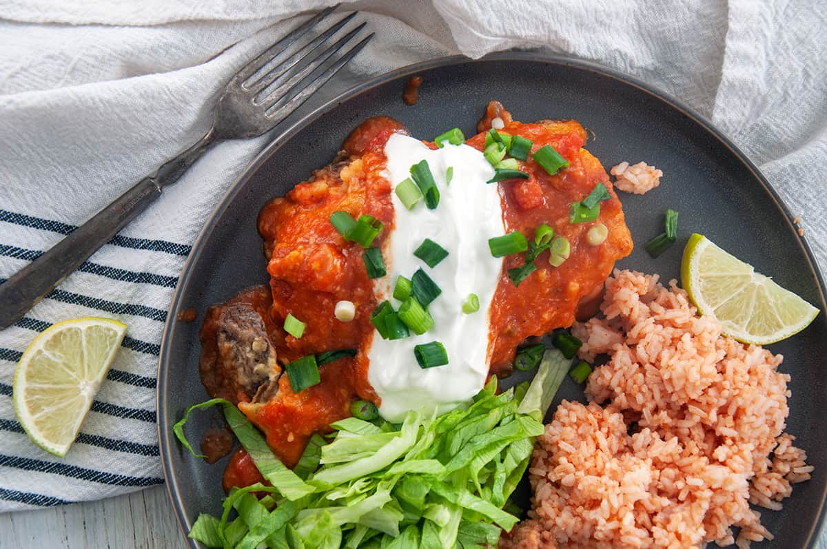 Shredded Beef Enchilada with sour cream on top and Spanish rice to the side.