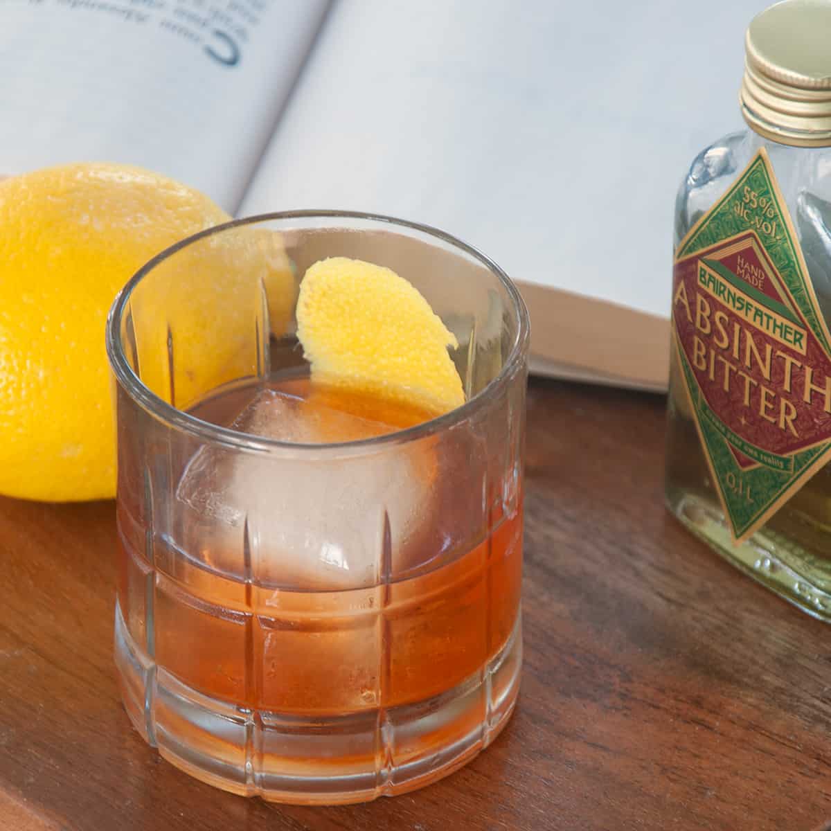 A Sazerac cocktail on a wood table.