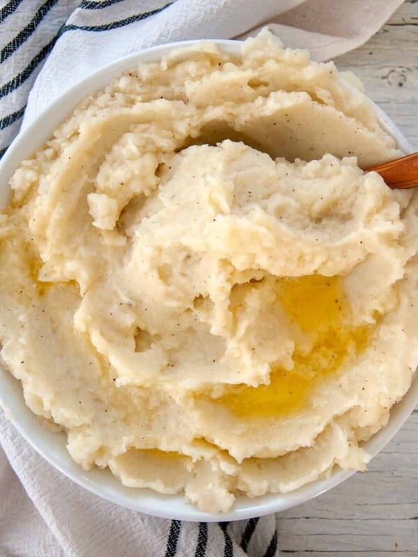 Large bowl of fluffy mashed potatoes with melted butter on top.