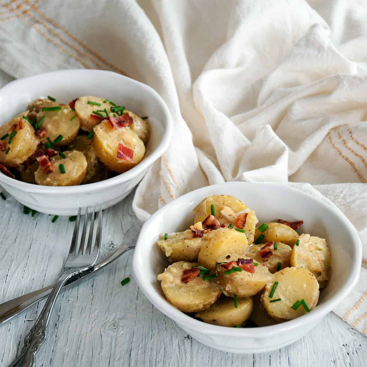 Two bowls of our German Potato Salad on a white background.