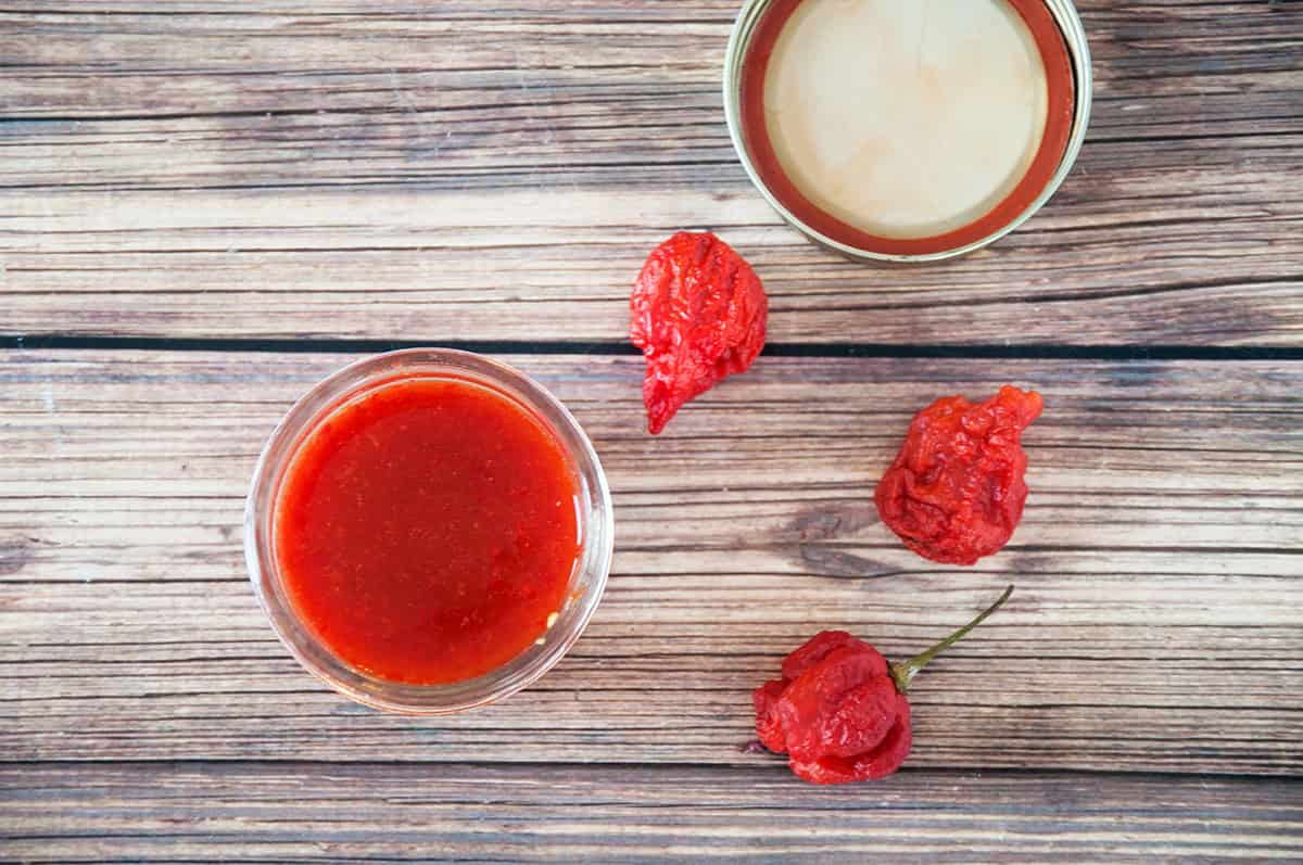 Overhead shot of the Reaper hot sauce with three Carolina reapers sitting on a table