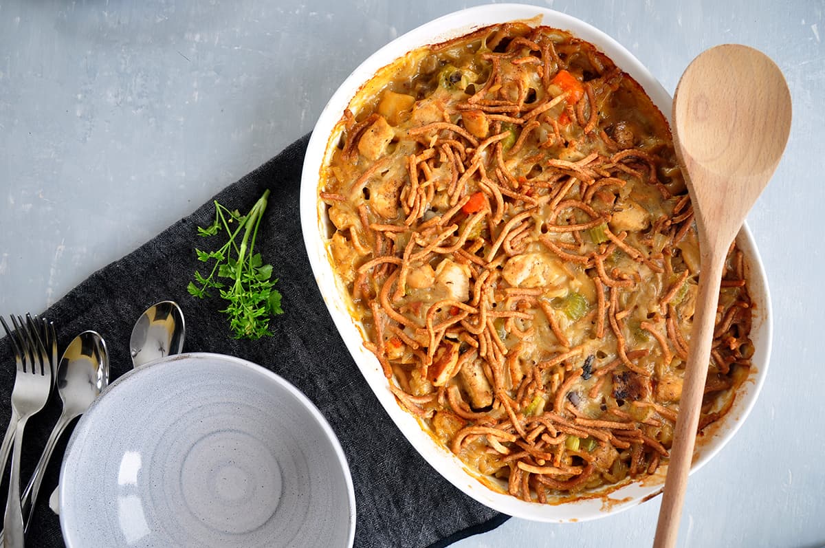 Chicken chow mein in a casserole dish with an empty bowl to the side.