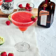 Frozen Strawberry Margarita with Cointreau and strawberries in the background.