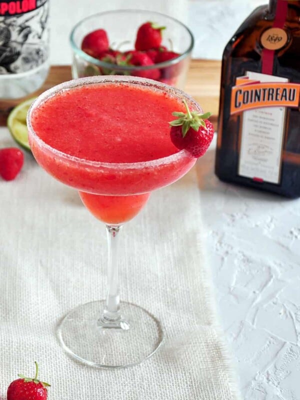 Frozen Strawberry Margarita with Cointreau and strawberries in the background.