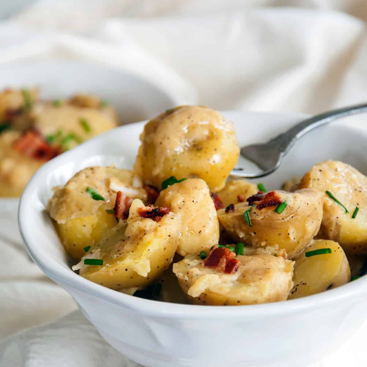 Kartoffelsalat in a bowl with a fork in one piece of a potato.