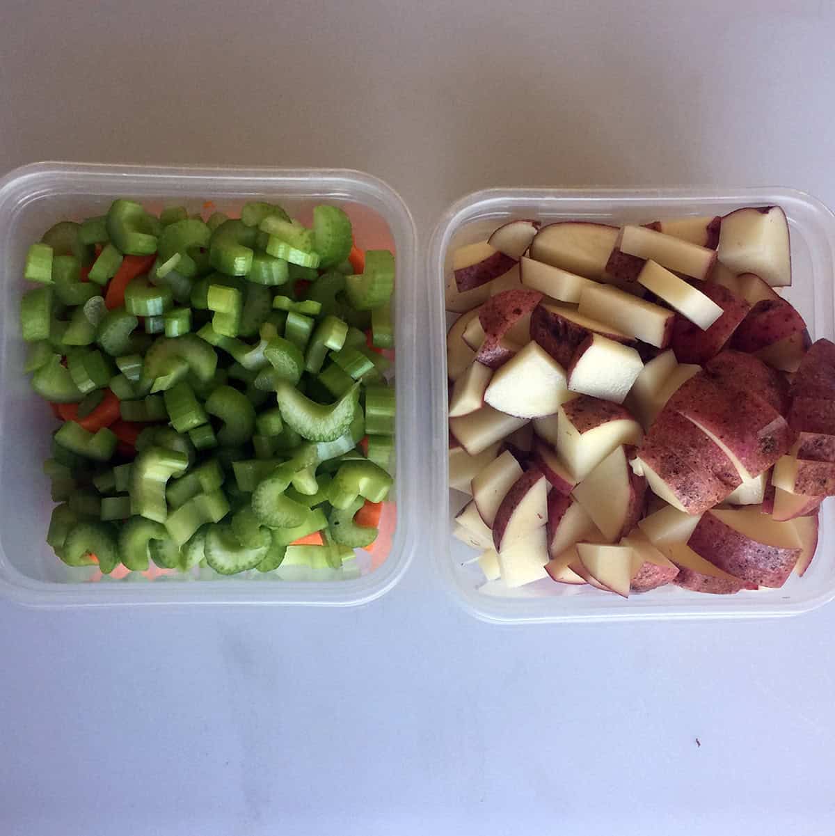 Chopped potatoes in a container. Celery and carrots in another container.