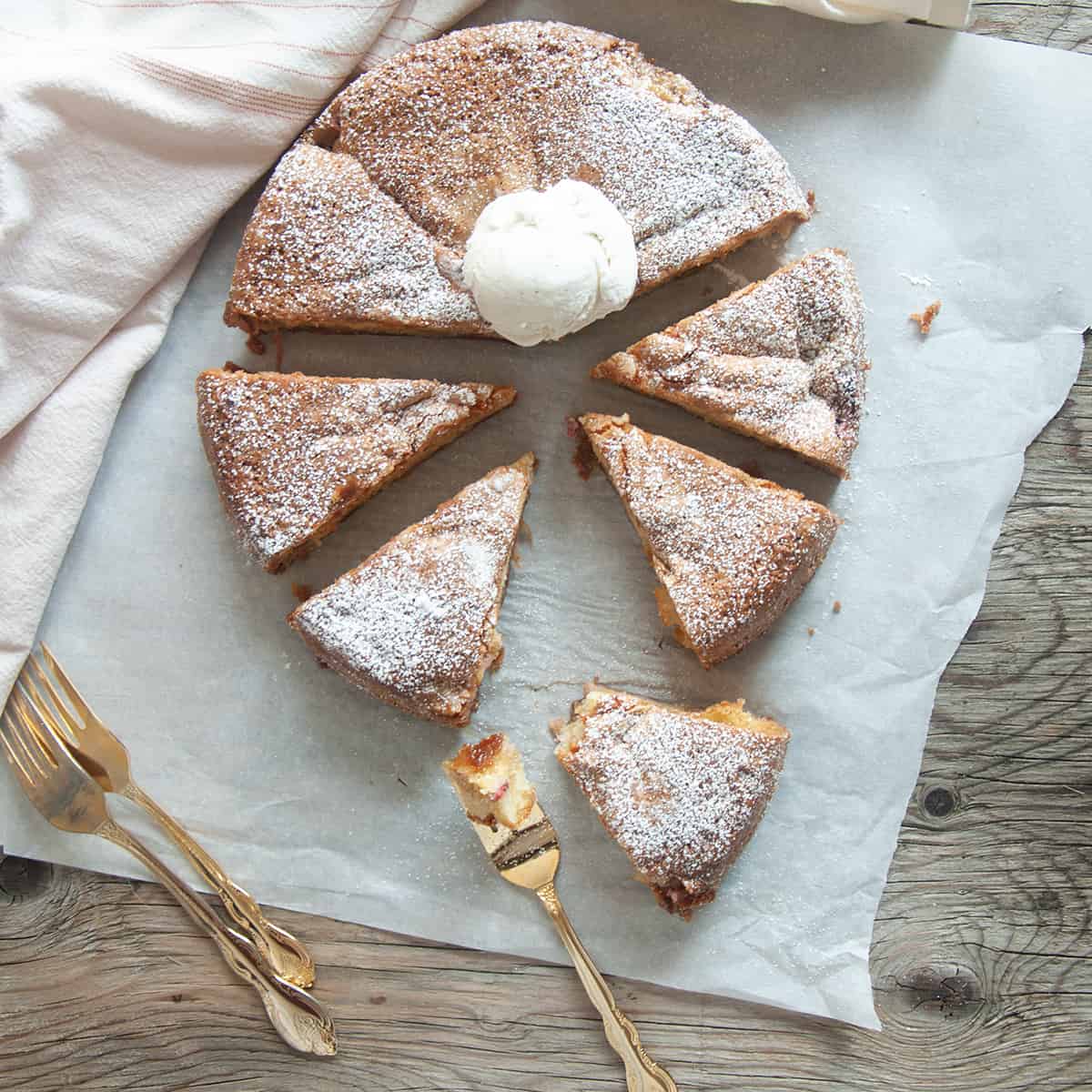 Norwegian Rhubarb Cake cut into eight pieces on white parchment paper.