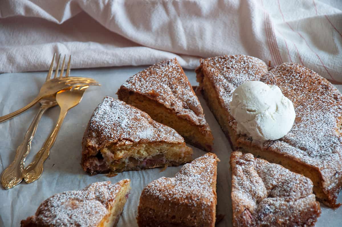 Rhubarb cake cut into pieces with a dollop of whipped cream on top!