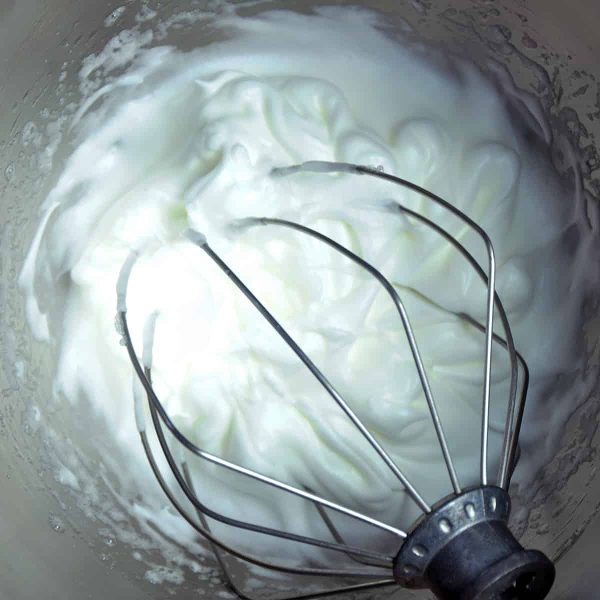 Whipped egg whites in KitchenAid mixing bowl.