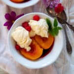 A white bowl containing a serving of peach melba.