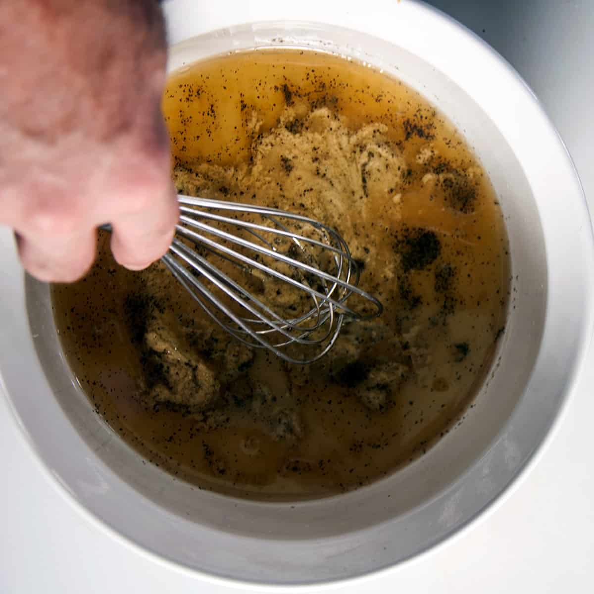 Wet ingredients being whisked in a white bowl.