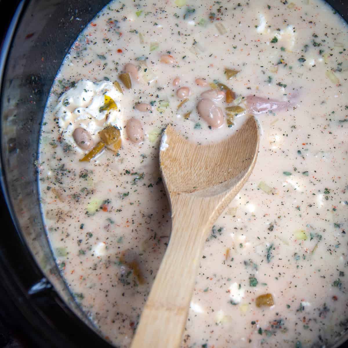 White chicken chili being mixed in a crockpot.
