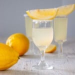 Two lemon drop shots on a white table.