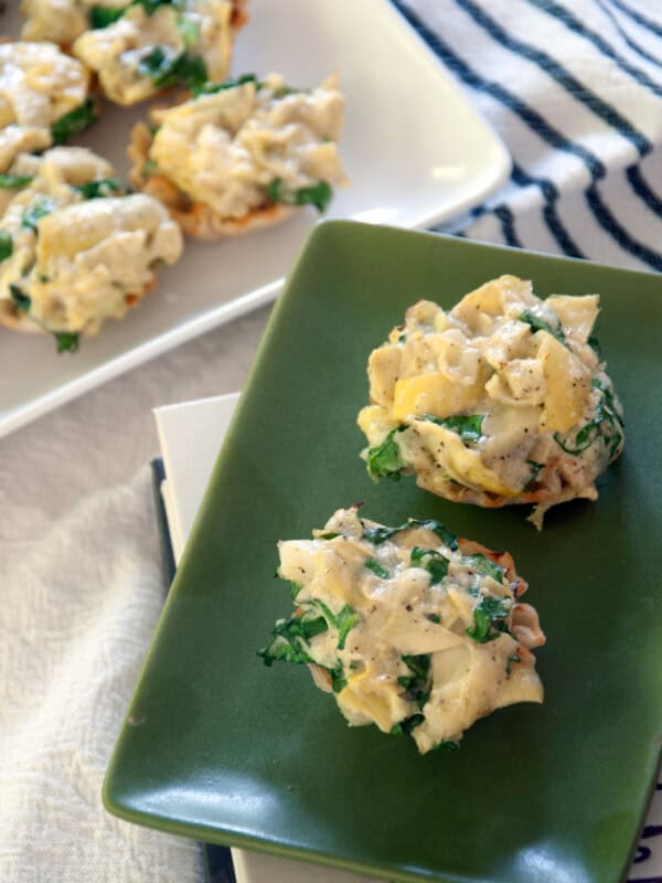 Two artichoke dip phyllo cups on a green plate.