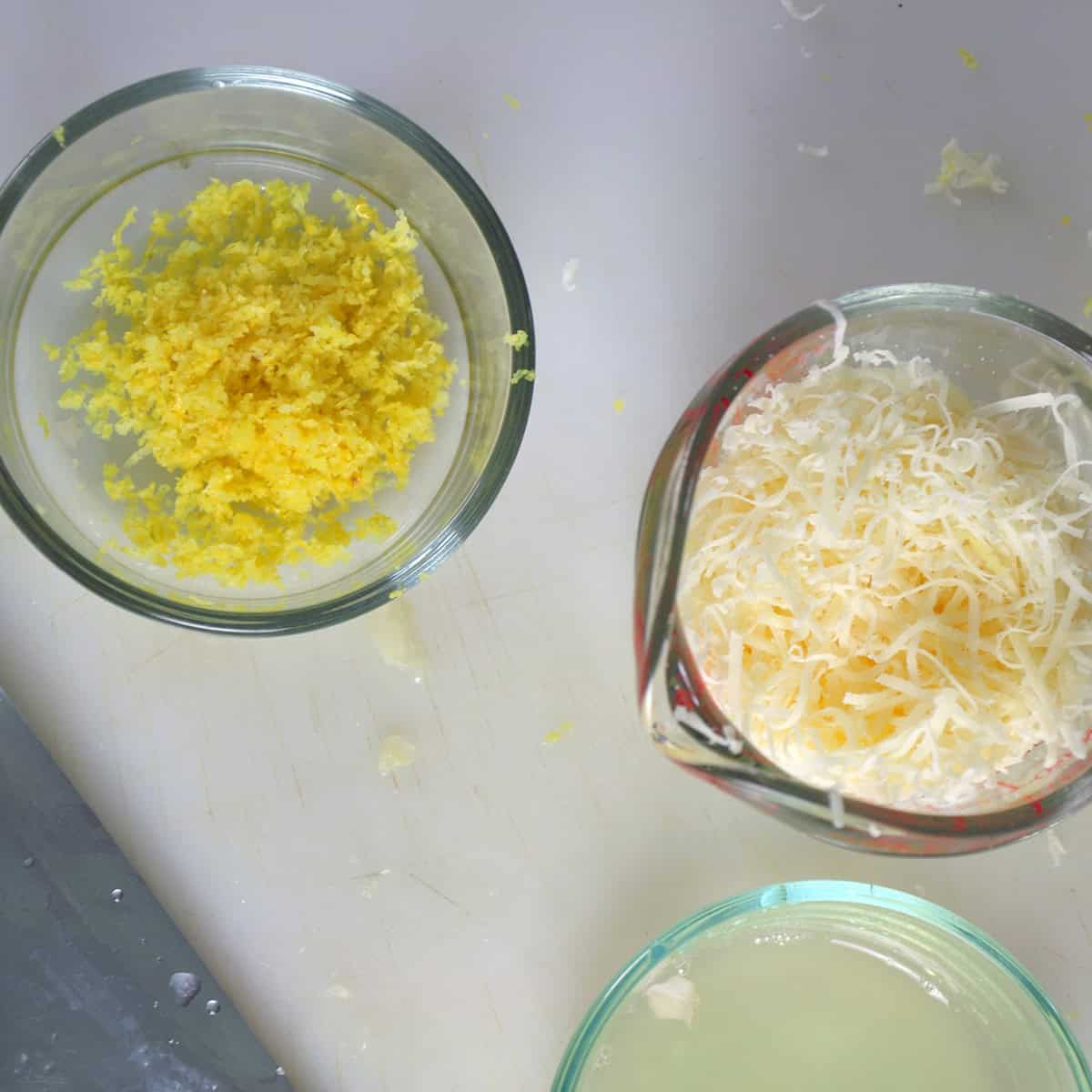 Lemon zest, lemon juice, and cheese in containers.