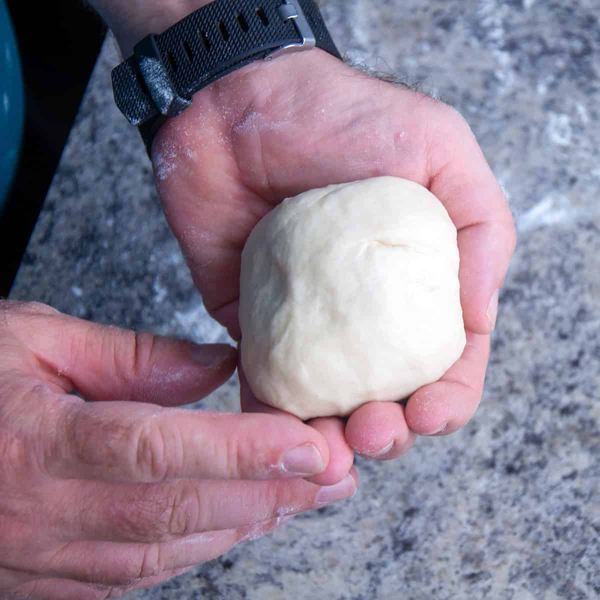 Hand holding a dough ball.