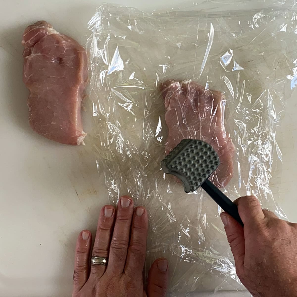 Pounding a pork cutlet with a mallet.