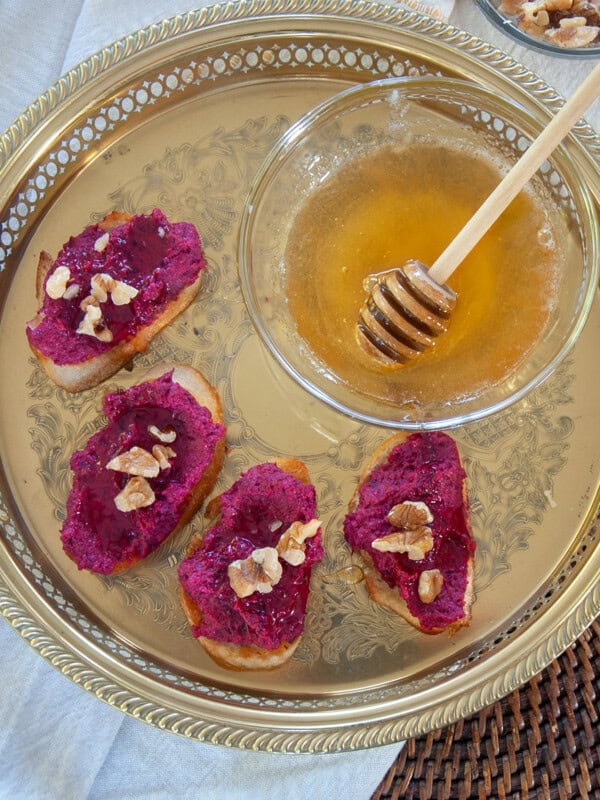 Roasted beets and ricotta crostini on a gold platter.